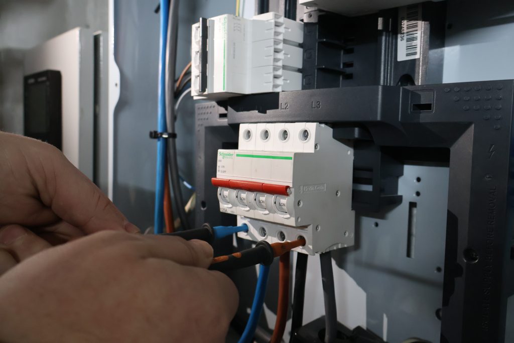 Close-up of a hand holding a multimeter probe, testing an electrical component